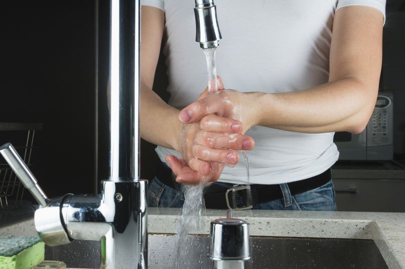 A person washing hands in sink